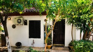 A small house with a tiled roof, a black door, and a white wall.