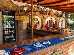 Un espace bar avec un mur en briques, un plafond en bois et une enseigne indiquant : « 7 JOURS, CHAQUE HEURE EST HEURE DE FAIRE DES AFFAIRES ».