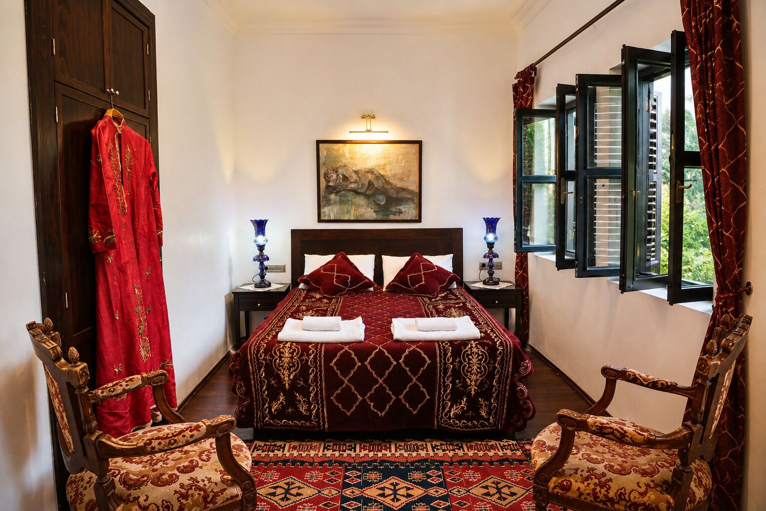 A bedroom with a large bed, two bedside tables, a painting on the wall, a window with shutters, and a red curtain.