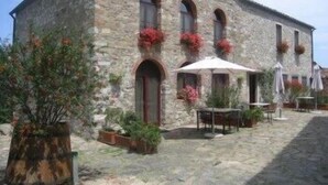 Un edificio de piedra con ventanas de arco y un patio con mobiliario para exteriores.