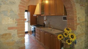 Una cocina con armarios de madera, un arco de ladrillo y un jarrón con girasoles.