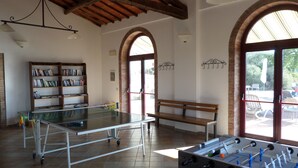 Una habitación amplia con mesa de fútbol, mesa de billar, una estantería y un banco.
