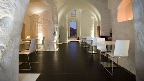 Un espace repas moderne avec des chaises et des tables blanches, un plafond en arc de cercle et une vue sur l’extérieur.