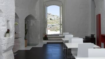 Un interior moderno con paredes blancas, suelo oscuro y vista a un paisaje rocoso a través de un arco.