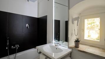 Ein modernes Badezimmer mit einem großen Spiegel, einem weißen Waschbecken, einer Dusche und einem Blumentopf.