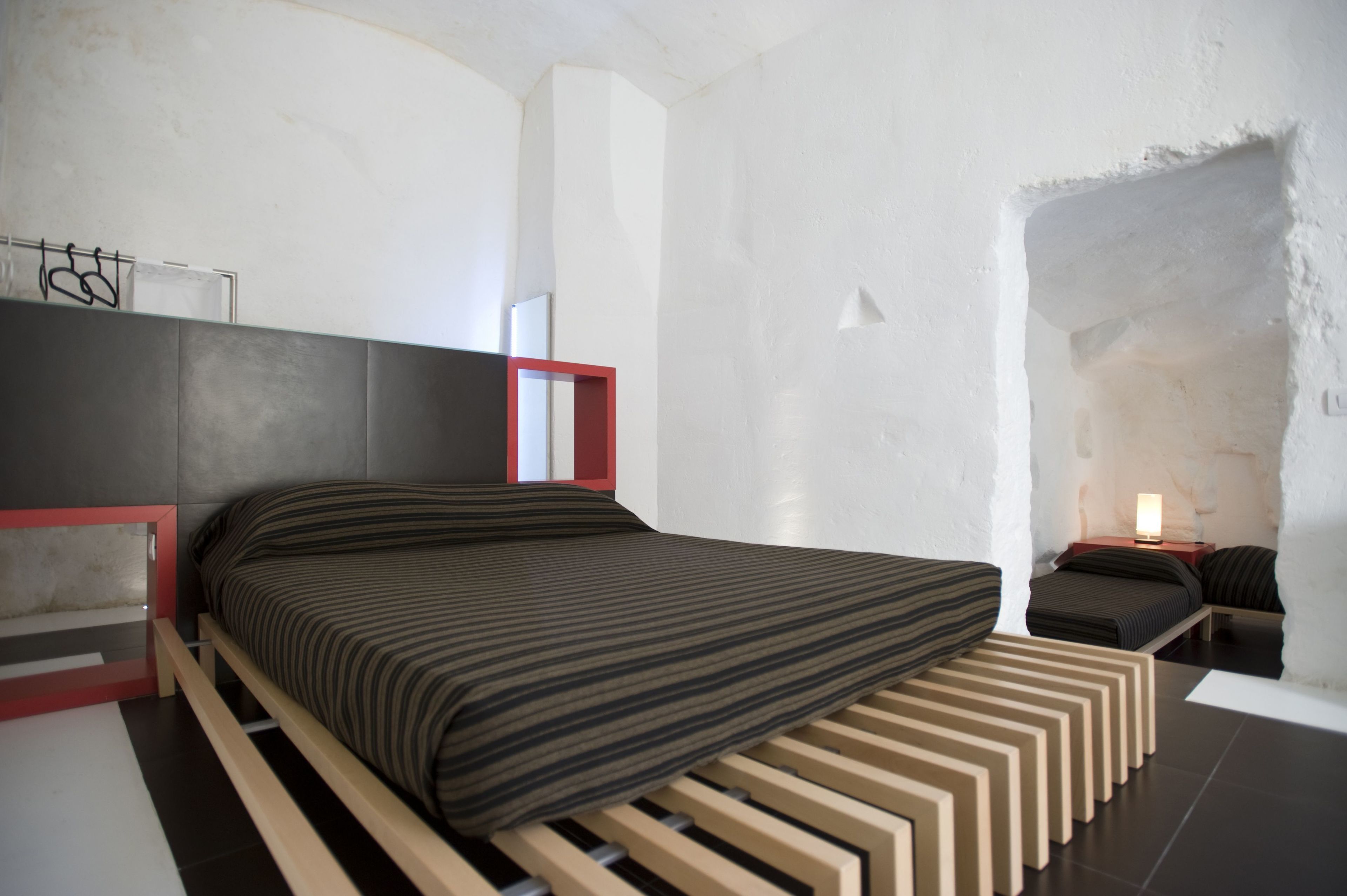 Un dormitorio moderno con una cama, una mesita de noche y un velador.