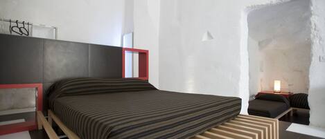 Un dormitorio moderno con una cama, una mesita de noche y un velador.