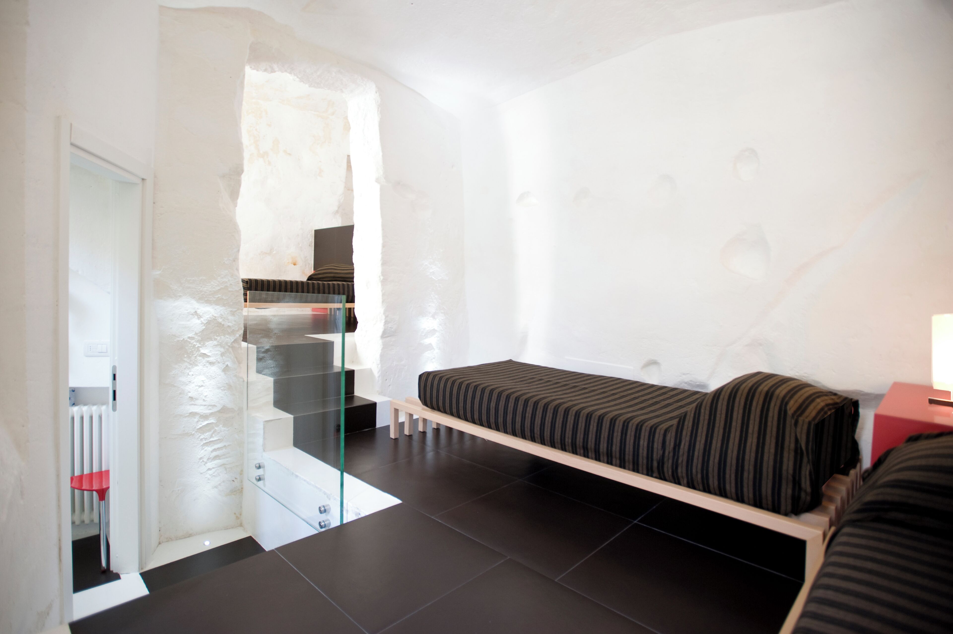 A modern bedroom with a bunk bed, a glass staircase, and a radiator.