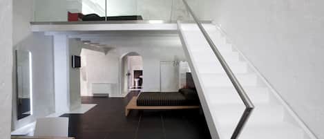 Um interior moderno com escadaria de vidro, sofá e um banco de madeira.