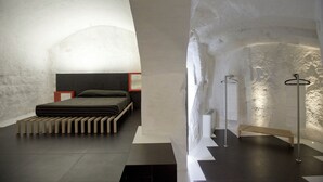 Une chambre à coucher moderne et minimaliste, avec un lit, des tables de chevet et un banc.