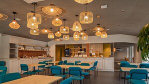 A modern restaurant interior with multiple dining tables and chairs, a bar area, and hanging wicker pendant lights. - Sure Hotel by Best Western Nantes Saint-Herblain (Saint-Herblain)