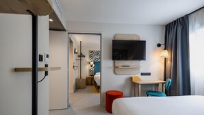 A hotel room with a bed, a desk, a chair, a TV, and a red ottoman. - Sure Hotel by Best Western Nantes Saint-Herblain (Saint-Herblain)