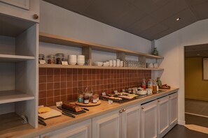 A kitchen with white cabinets, a wooden countertop, and shelves with jars and bowls. - Sure Hotel by Best Western Nantes Saint-Herblain (Saint-Herblain)