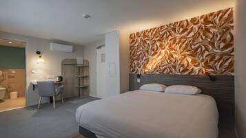 A modern hotel room with a large bed, a desk, a chair, and a bathroom.