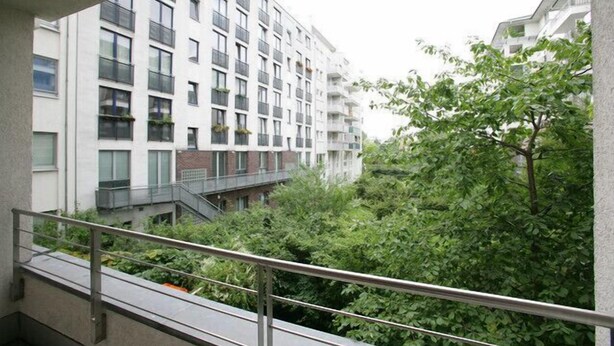 A modern apartment building with balconies, a view of greenery, and a metal railing. - Apartment Engel (Berlin)