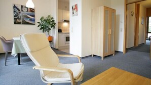 A room with a white chair, a small table, a plant, and a wardrobe. - Apartment Engel (Berlin)