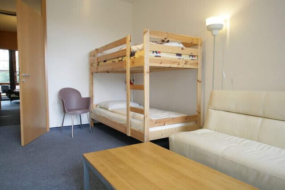 A bunk bed room with a sofa and a table.
