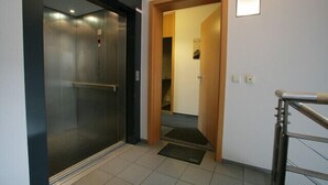 A modern elevator with a glass door and a wooden door leading to a hallway. - Apartment Engel (Berlin)