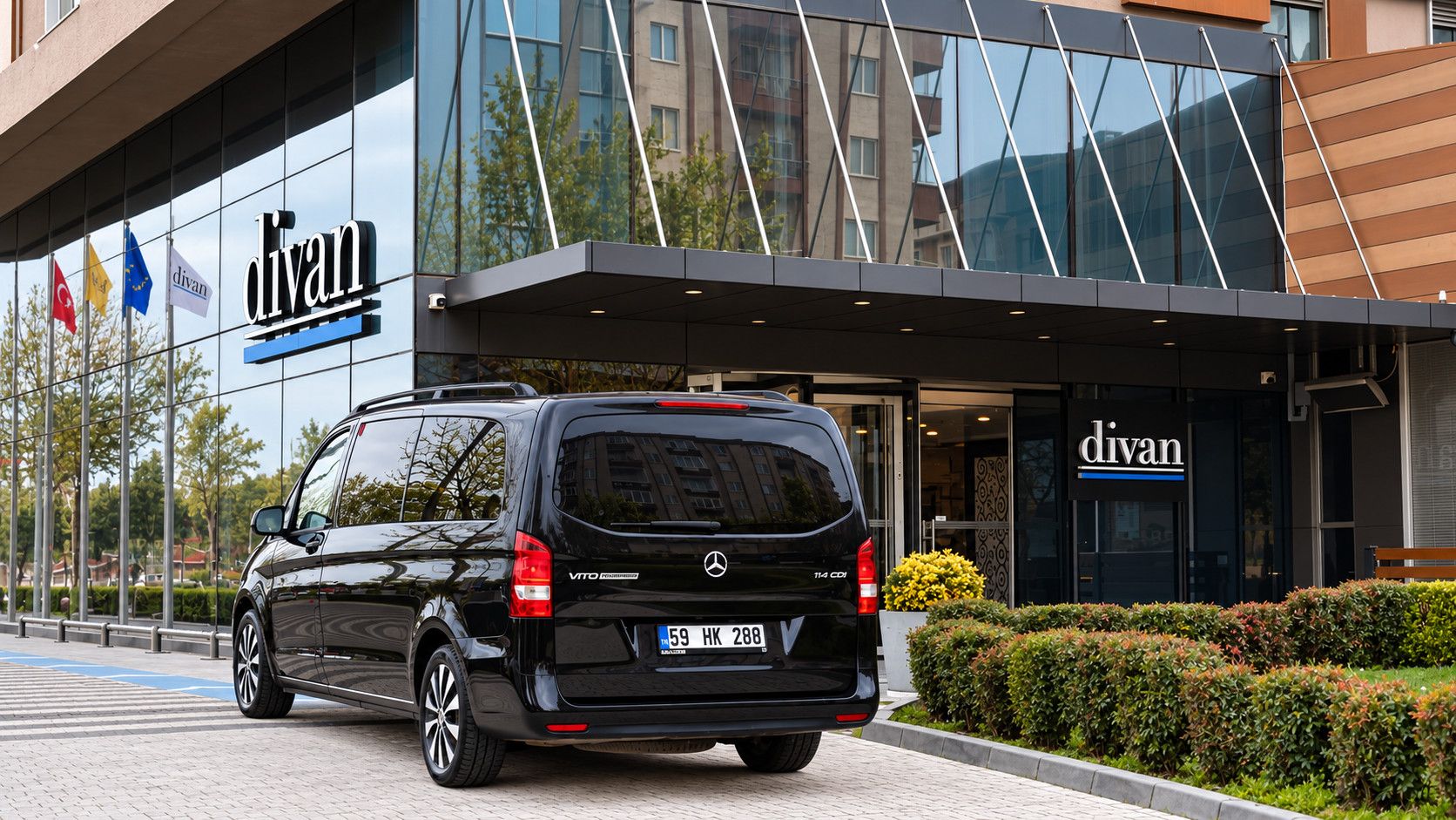 A black Vito van parked in front of a building with a glass facade and the name 'divan' displayed.