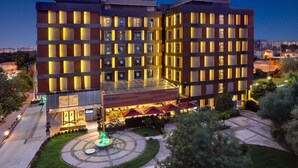 A modern hotel with multiple floors, a central courtyard, and a well-lit entrance. - Divan Corlu (Corlu)