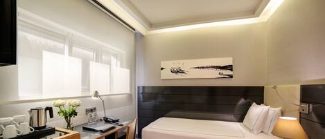 Una habitación de hotel moderna con cama, escritorio, silla y un ventanal grande.