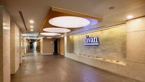 A hotel corridor with a 'divan' sign, recessed lighting, and a tiled floor.