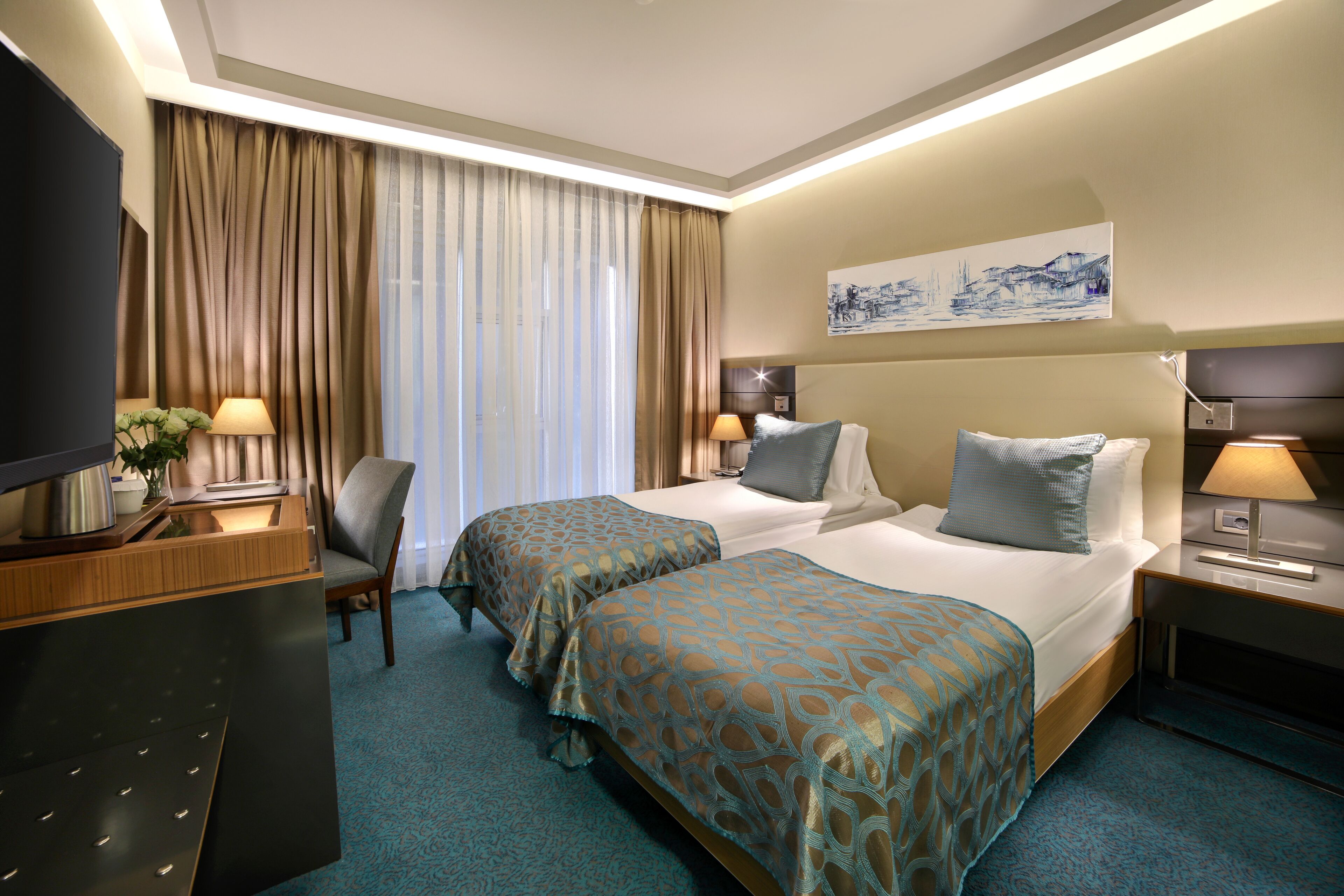 Une chambre d’hôtel avec deux lits, un bureau, une télévision et une grande fenêtre avec des rideaux.