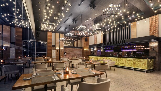 A modern restaurant interior with multiple dining tables, chairs, and a bar area. - Divan Corlu (Corlu)