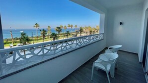 A balcony with a view of the sea and palm trees.