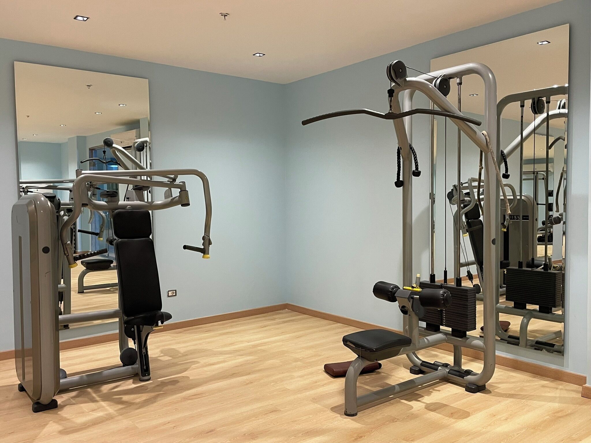 Un gimnasio con equipo de ejercicio, una banca y un espejo grande.