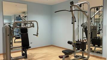 Un gimnasio con equipo de ejercicio, una banca y un espejo grande.