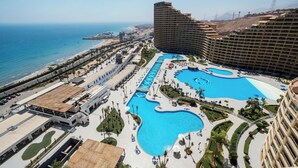 A resort with multiple swimming pools, a beach, and high-rise buildings.