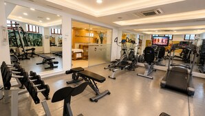 A gym with various exercise equipment, mirrors, and a television.