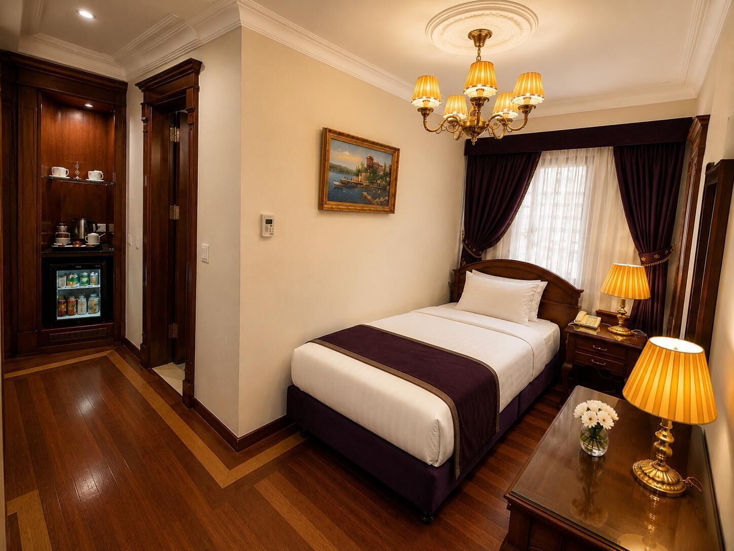 A hotel room with a bed, bedside table, lamp, and a painting on the wall.