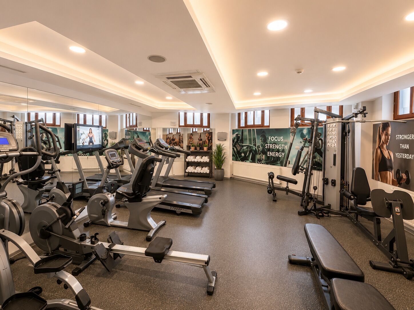 A gym with treadmills, weight machines, and a wall with motivational posters.