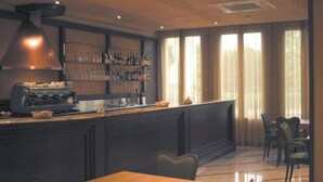 Una zona de bar con mostrador, estanterías llenas de botellas y un área de asientos con sillas y una mesa.