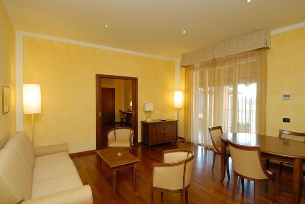 Une chambre d’hôtel avec un canapé, une table à manger avec des chaises, un petit meuble et un miroir.
