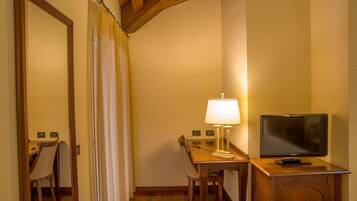 Ein Hotelzimmer mit einem Holztisch, einer Lampe, einem Fernseher und einem Sessel.
