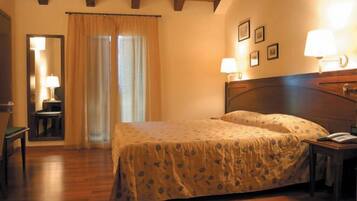 A bedroom with a wooden bed, a nightstand, a chair, a desk, a mirror, and a window with curtains.