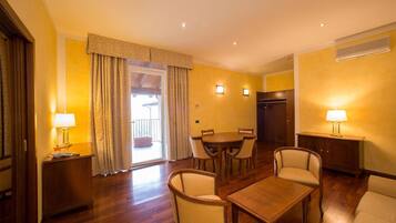 A hotel room with a dining area, a sofa, a table, and a lamp.