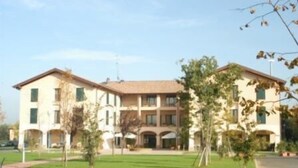 Un edificio de dos plantas con fachada simétrica, varios ventanales y una entrada central.