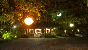 A building with a sign reading "VINEYARD" at night, surrounded by trees and a parked car. - Vinh Hung Riverside Resort & Spa (Da Nang)
