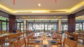 A spacious dining area with wooden tables and chairs, large windows, and a decorative ceiling. - Vinh Hung Riverside Resort & Spa (Da Nang)