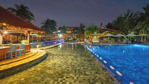 A pool area with lounge chairs and umbrellas, a bar area with chairs, and a tiled walkway. - Vinh Hung Riverside Resort & Spa (Da Nang)