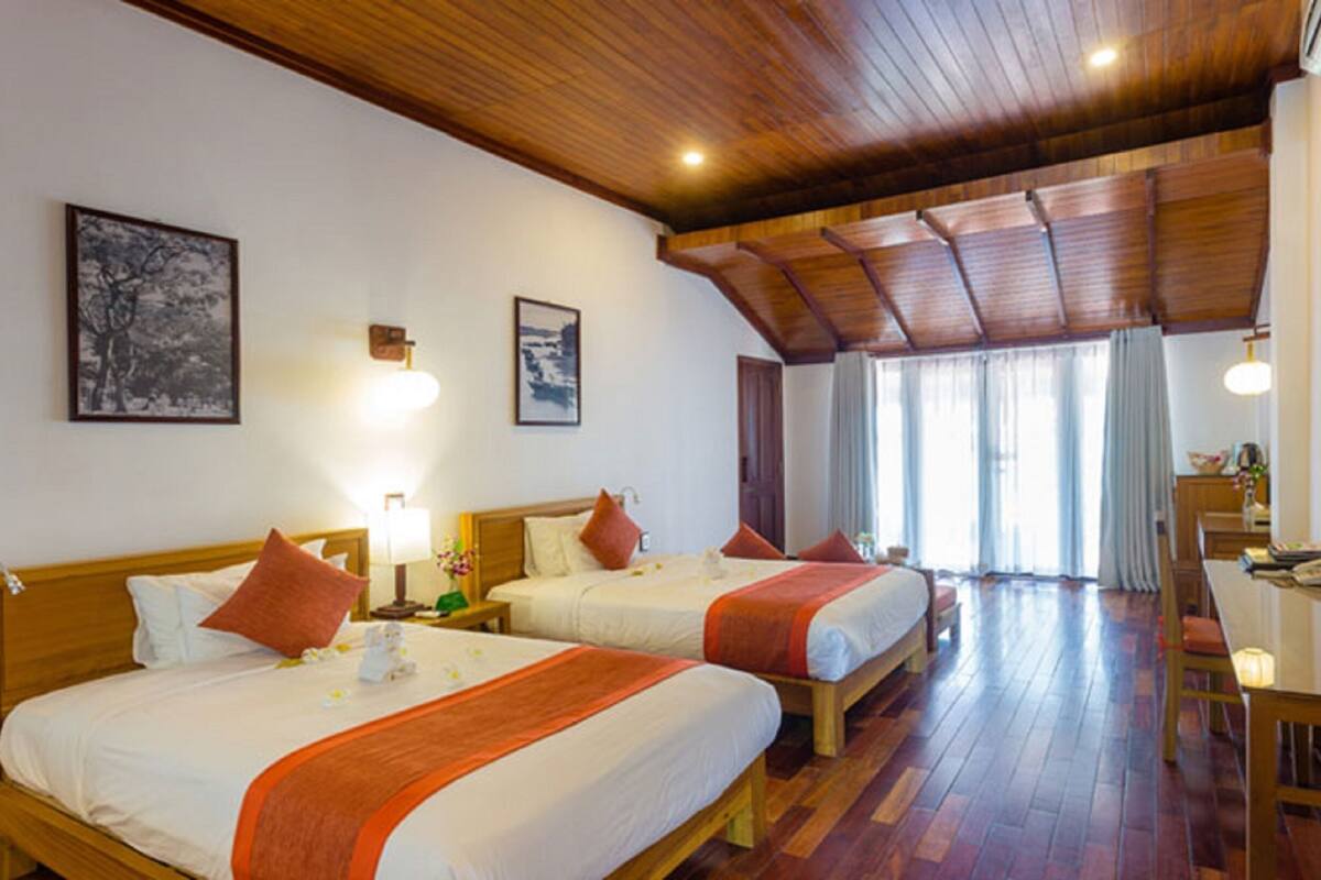 A hotel room with two beds, wooden flooring, a TV, and artwork on the walls.