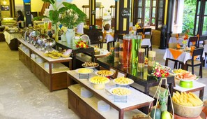 A buffet setup with various food items and drinks, including fruits, pastries, and condiments.