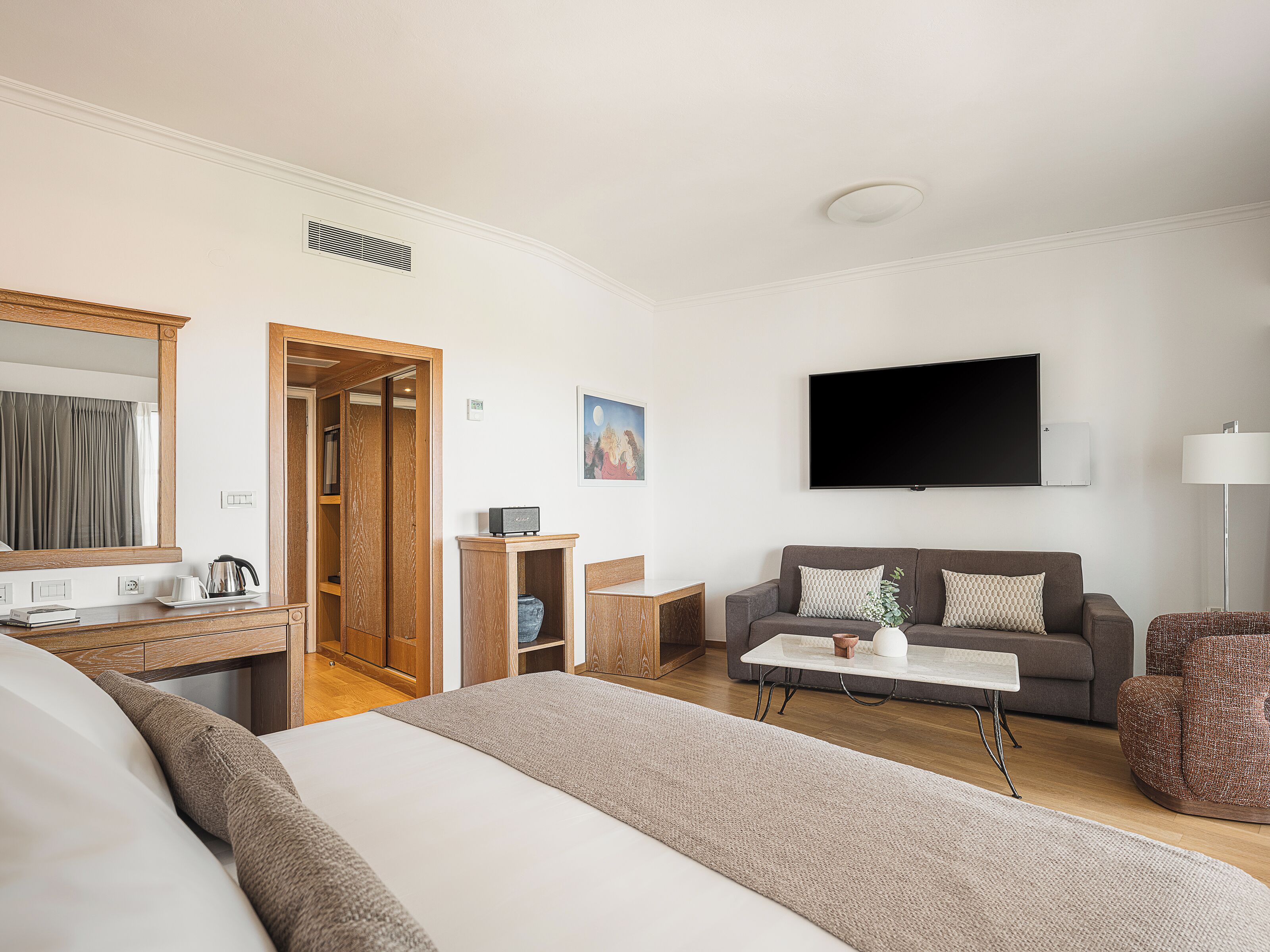 Une chambre d’hôtel comprenant un lit, un bureau, une télévision, un canapé et un fauteuil.
