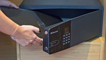 A black electronic device with a keypad and a display screen, held by a person wearing a bracelet.