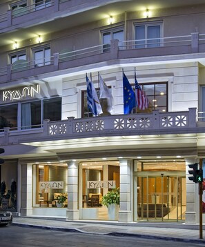 A hotel with a prominent sign, multiple flags, and a well-lit entrance. - Kydon, The Heart City Hotel (Chania)