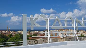 A white sign with the word "KIAON" against a backdrop of a coastal town with buildings and a clear sky.